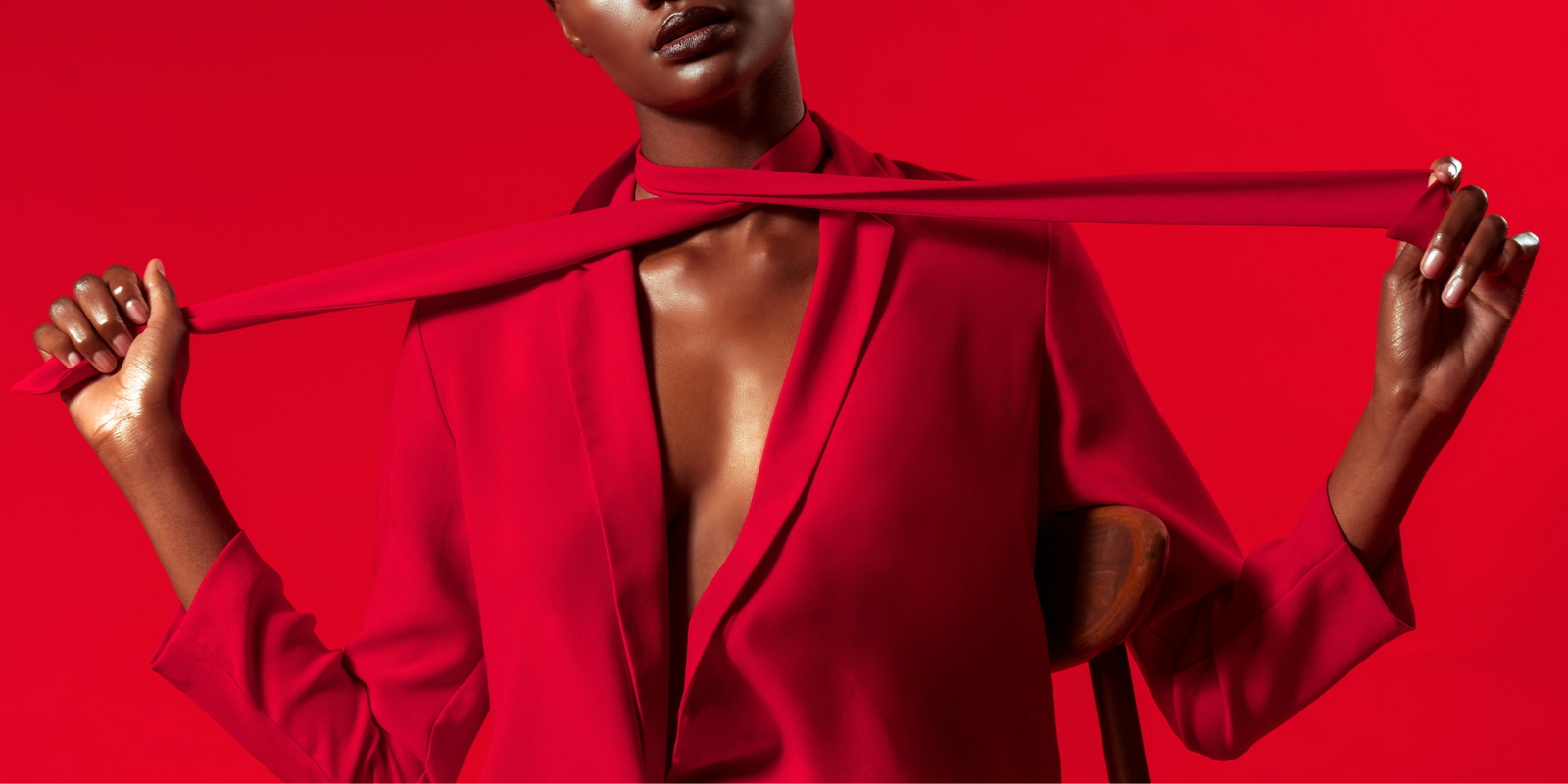 Modelo con blusa roja, sosteniendo una cinta roja, fondo rojo, destacando el estilo y diseño.