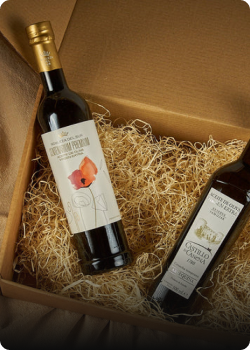 Cajas con botellas de aceite de oliva, presentadas en una caja con relleno de paja, ideal para regalos.