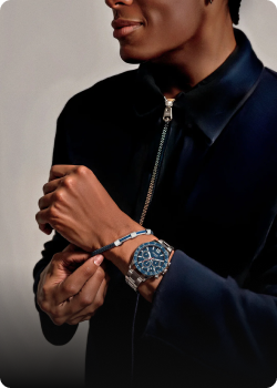 Hombre con chaqueta oscura mostrando una pulsera y reloj, destacando estilo y elegancia.