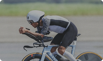 Atleta en bicicleta de triatlón, enfocado en la velocidad y el rendimiento durante una competencia.