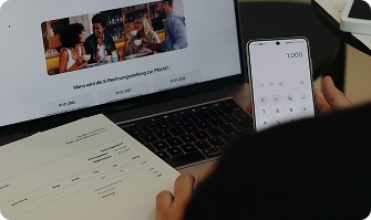 Persona usando un teléfono móvil mientras revisa una pantalla de computadora con diseño de agencia Shopify.