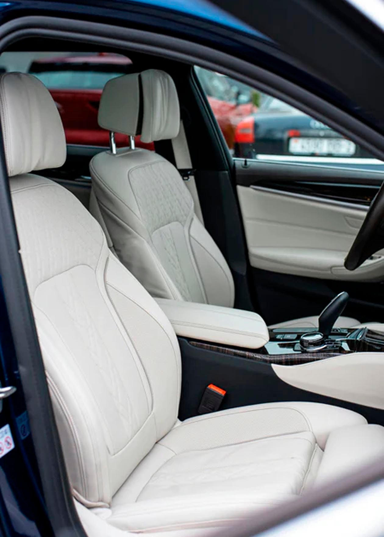 Asientos de cuero claro en el interior de un coche, con detalles en el tablero y palanca de cambios.