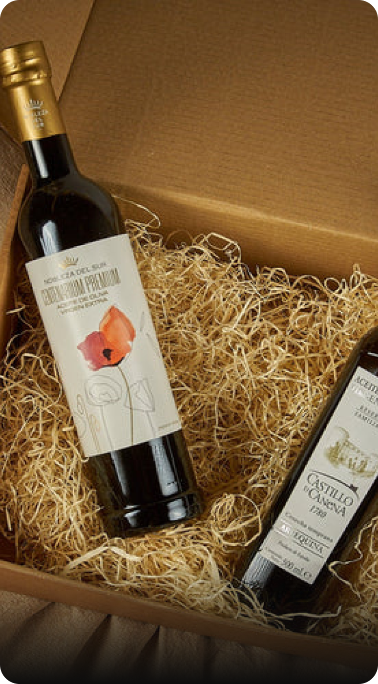 Dos botellas de vino en una caja de cartón con relleno de paja, destacando su presentación.