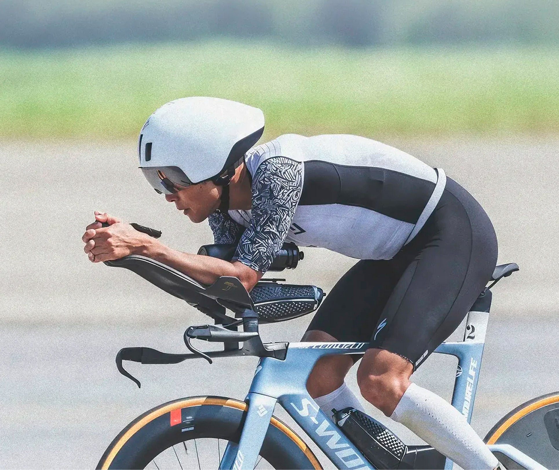 Ciclista en posición aerodinámica sobre una bicicleta de carreras, con casco y ropa ajustada.