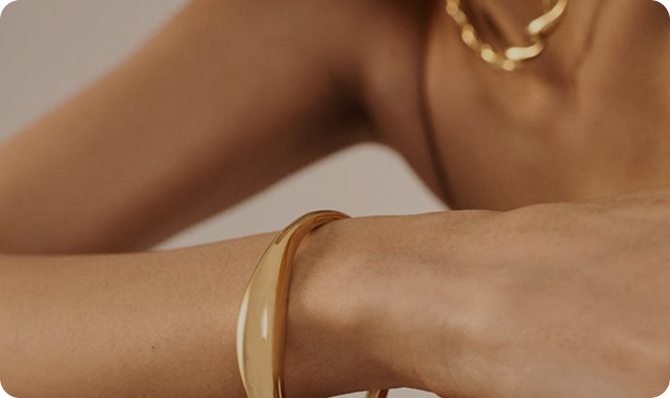 Brazo con pulsera dorada y collar, mostrando elegancia y estilo en accesorios de moda.