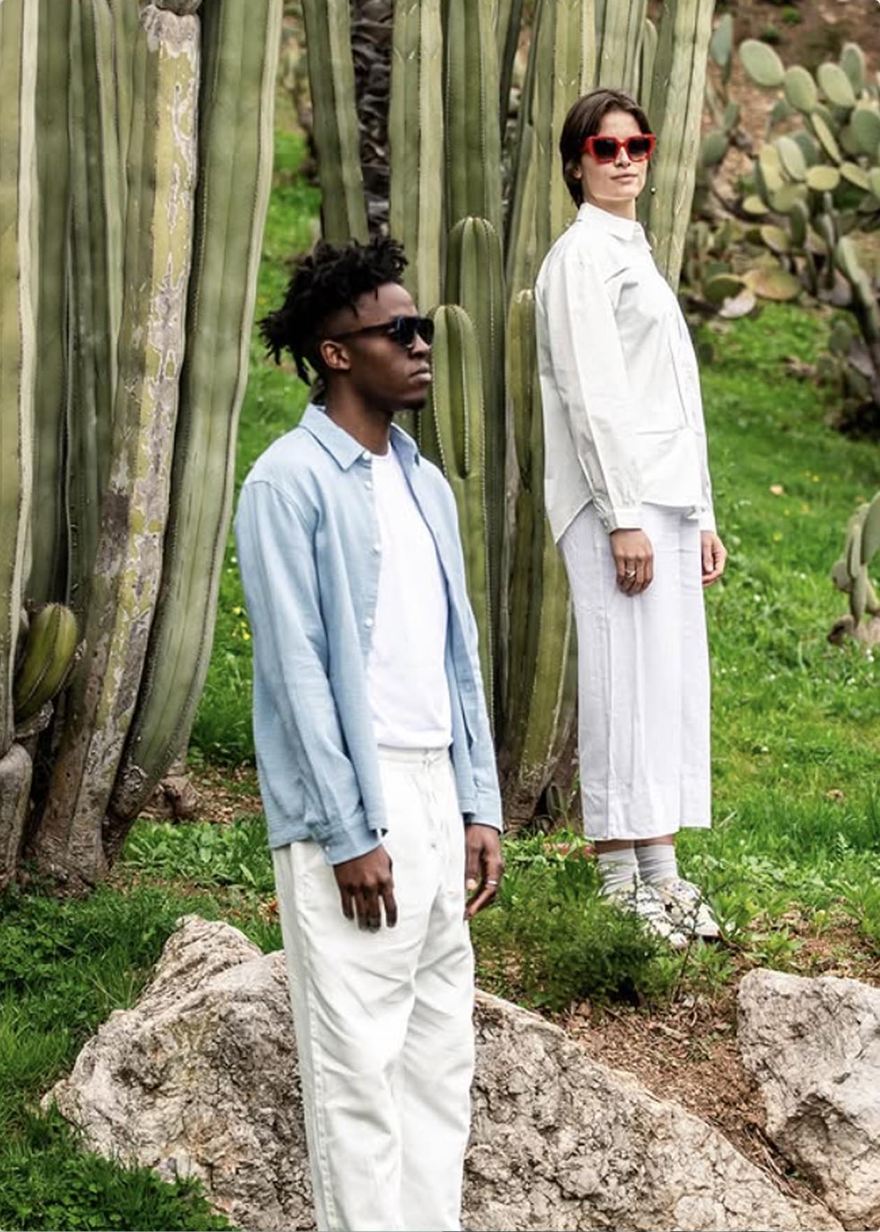 Dos personas posando entre cactus, una con camisa azul y otra con abrigo blanco, en un entorno natural.